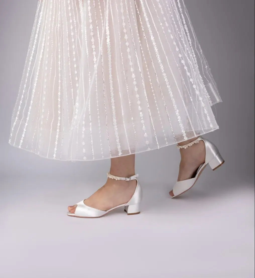 Zapatos de novia Fiona en satén marfil con puntera peep toe, sandalia tacón bajo de 3,8 cm y pulsera de perlas keshi para un look elegante y cómodo.